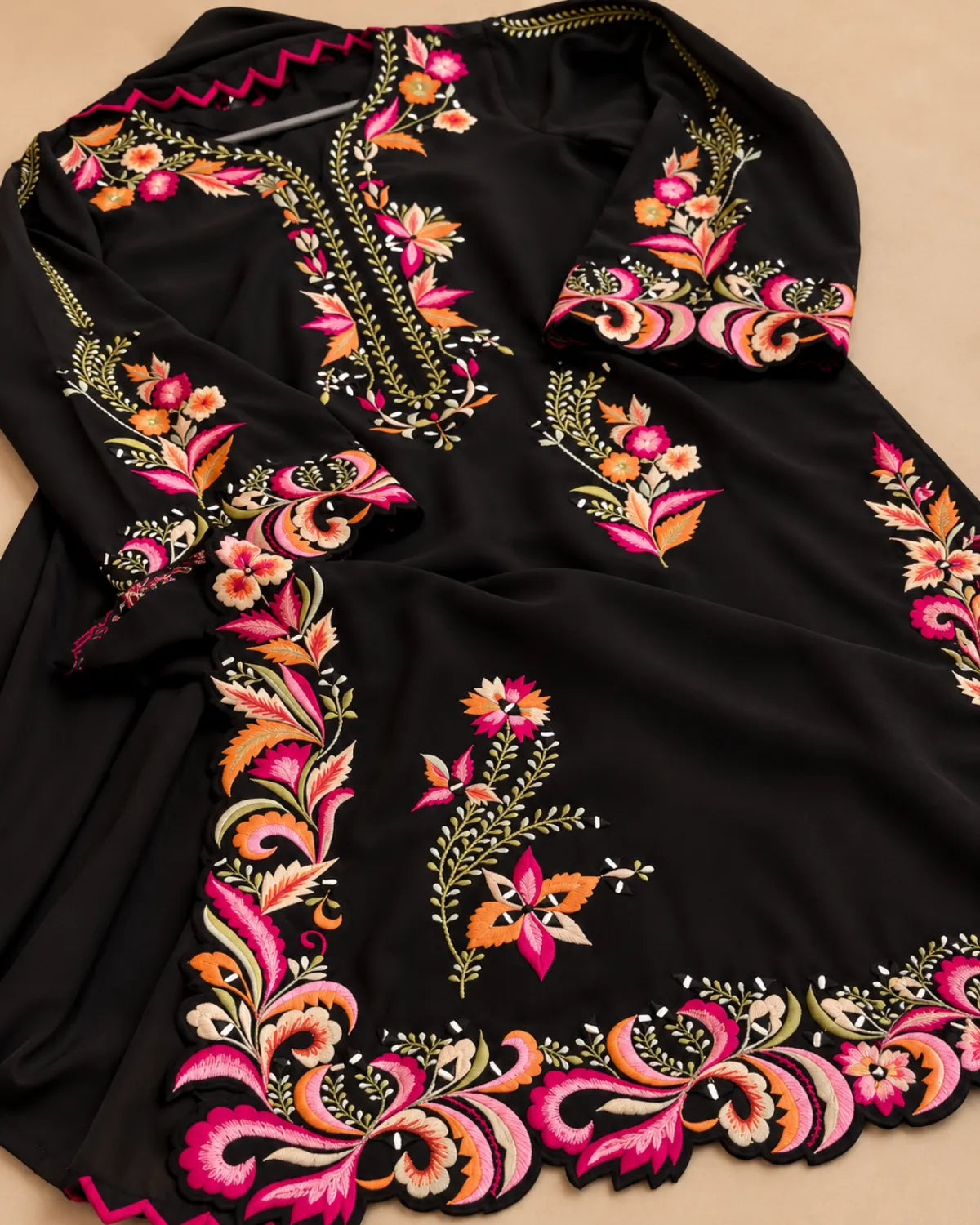 A black long-sleeve tunic or kurta with vibrant, colorful floral embroidery in pink, orange, yellow, and green along the neckline, sleeves, and hem.