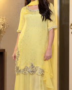 A woman wearing a light yellow ethnic kurta set with silver sequin embellishments, a matching dupatta, and a flared skirt, standing indoors.