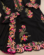 Black embroidered fabric garment with vibrant floral and paisley embroidery in pink, orange, yellow, and green, shown in a close-up flat lay.
